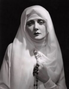 Mary Nolan in a white nun's veil with her hands clasped in prayer, a still from the German film 'Memoirs of a Nun.'