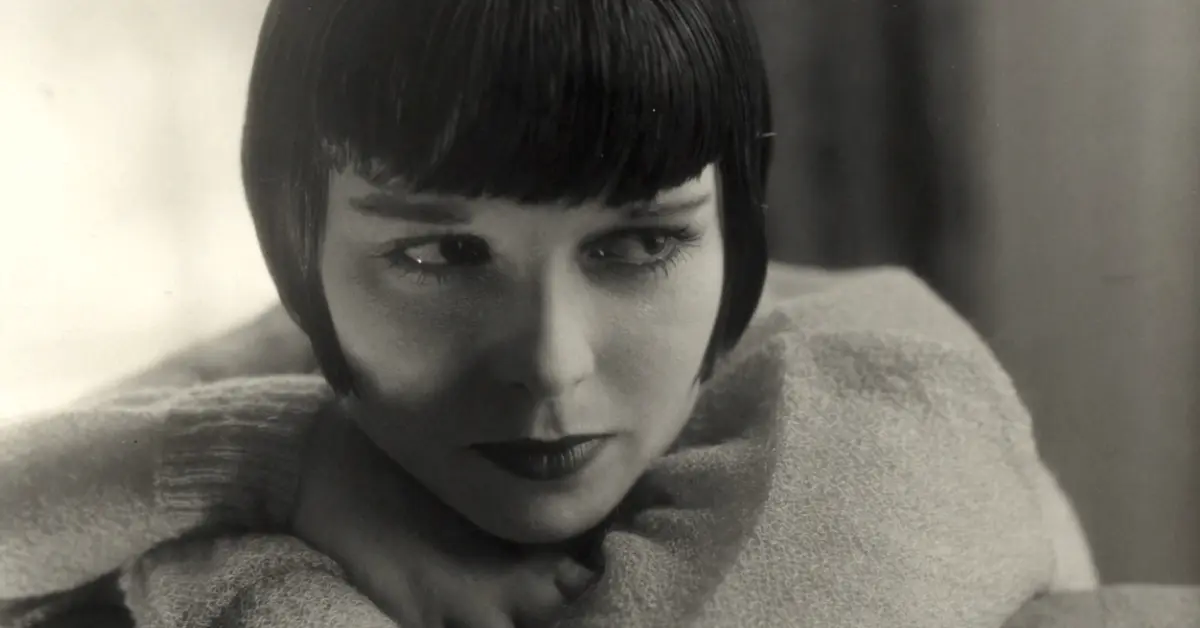 Louise Brooks photographed by Edward Steichen in August 1928, leaning over a chairback in a soft light wrap, wearing the dark bob that became her signature. Cropped from the full frame.