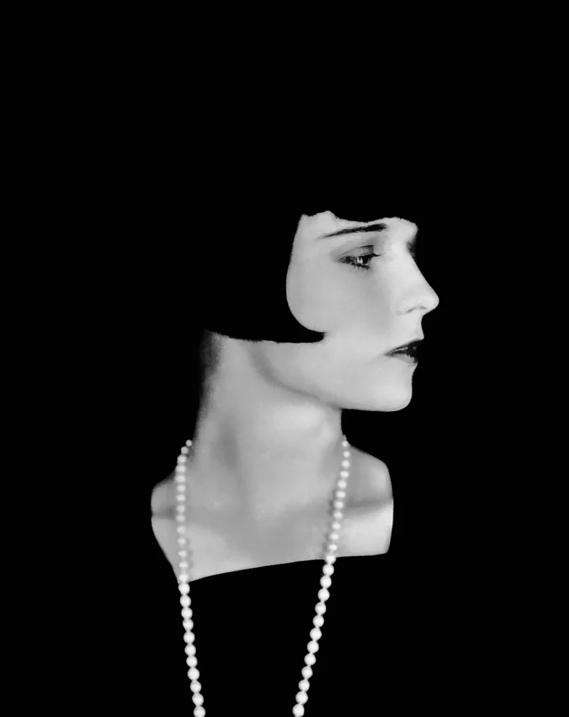 Louise Brooks in profile against a black ground, wearing a long strand of pearls falling from her bare shoulder; studio portrait by Eugene Robert Richee for Paramount, 1928